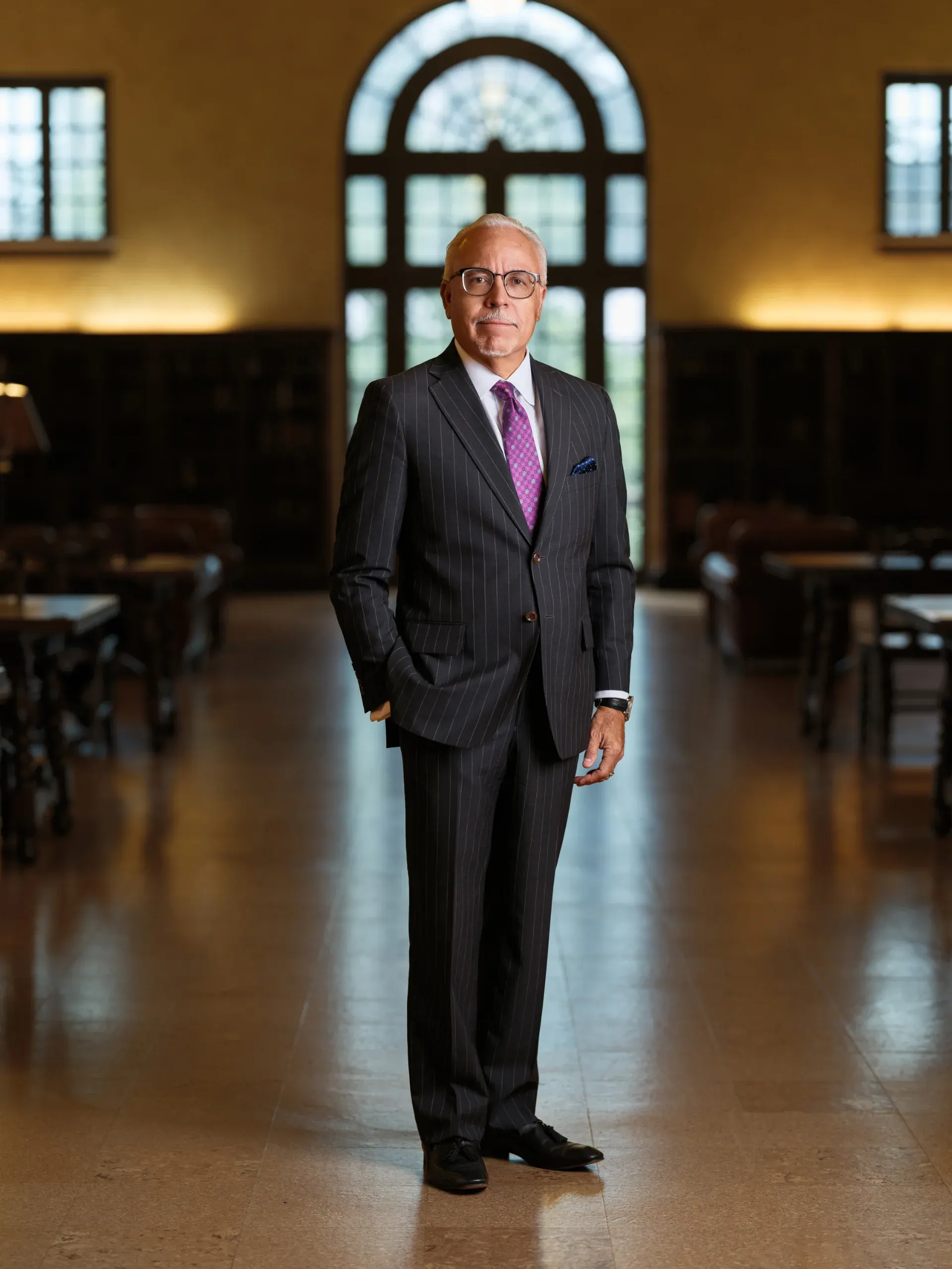Houston attorney portrait of a man in a dark suit and purple tie standing in a law library