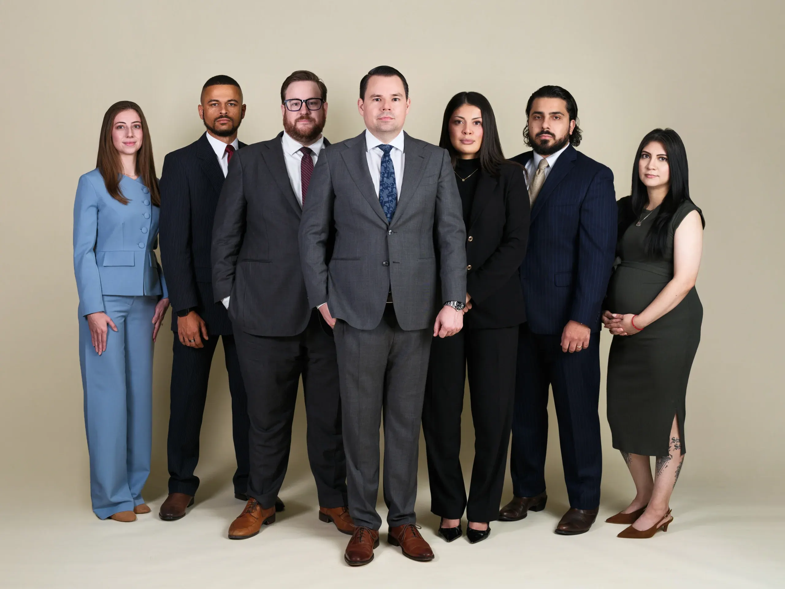 Houston law firm team of seven in suits and business dress on a tan studio backdrop