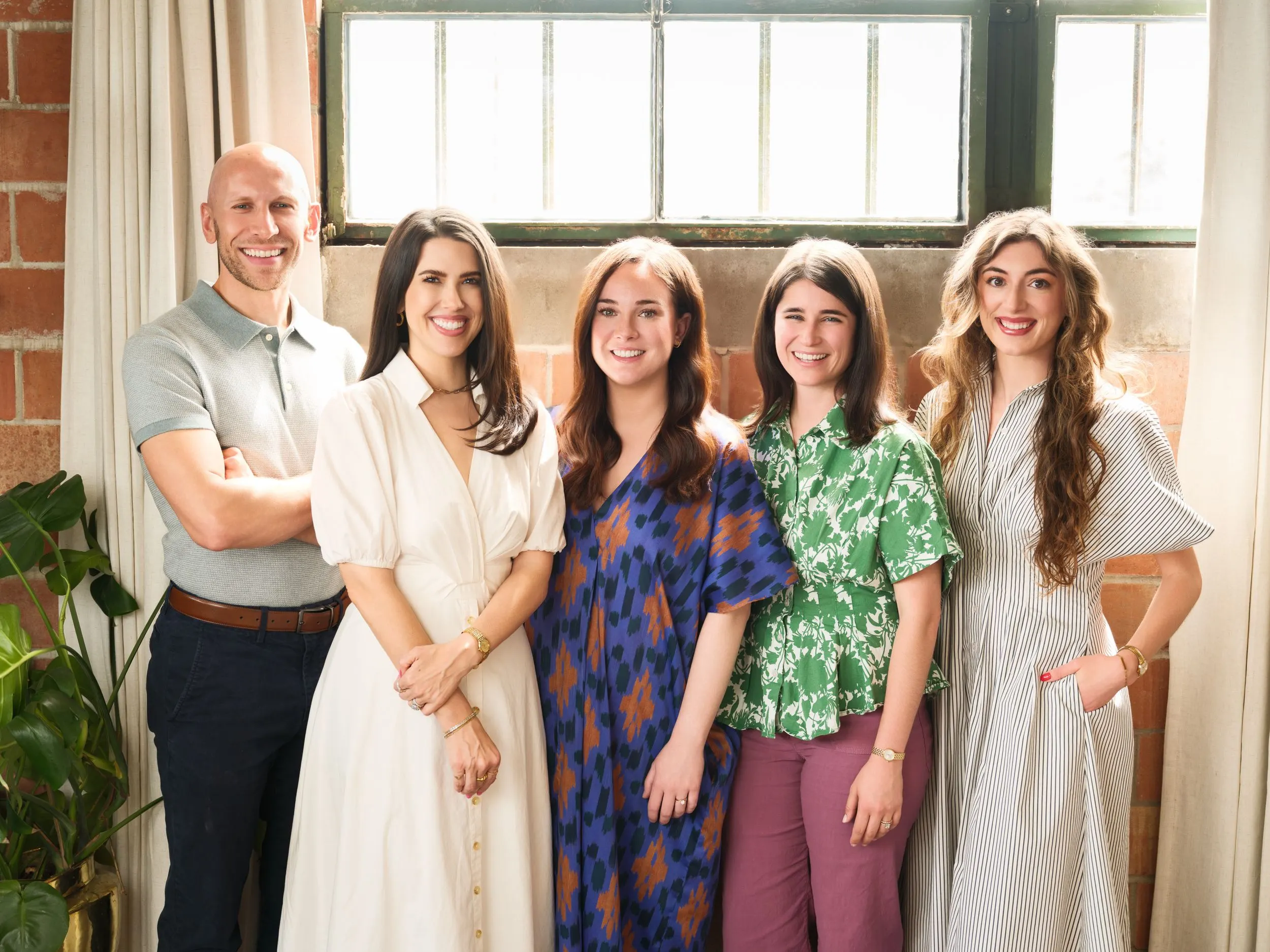 The five-person Katie Hilburn Homes team in front of a backlit studio window near Downtown Houston