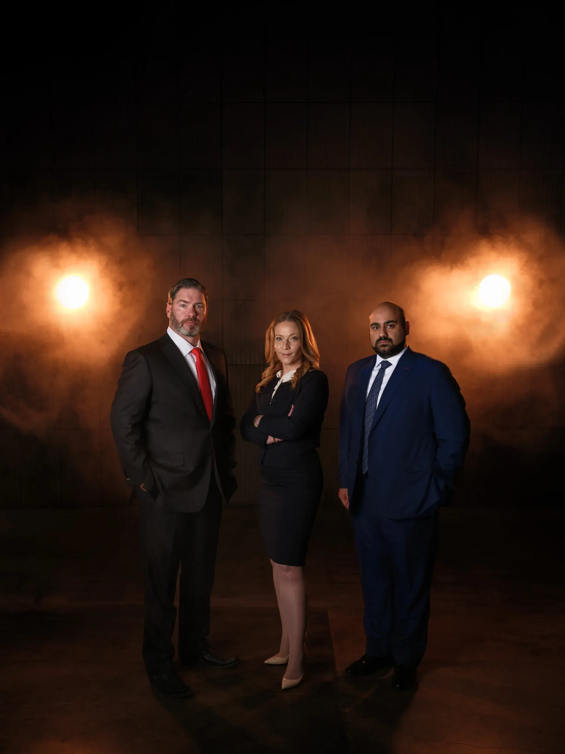 Three Houston attorneys in a dramatic dark portrait with warm lights and haze behind them