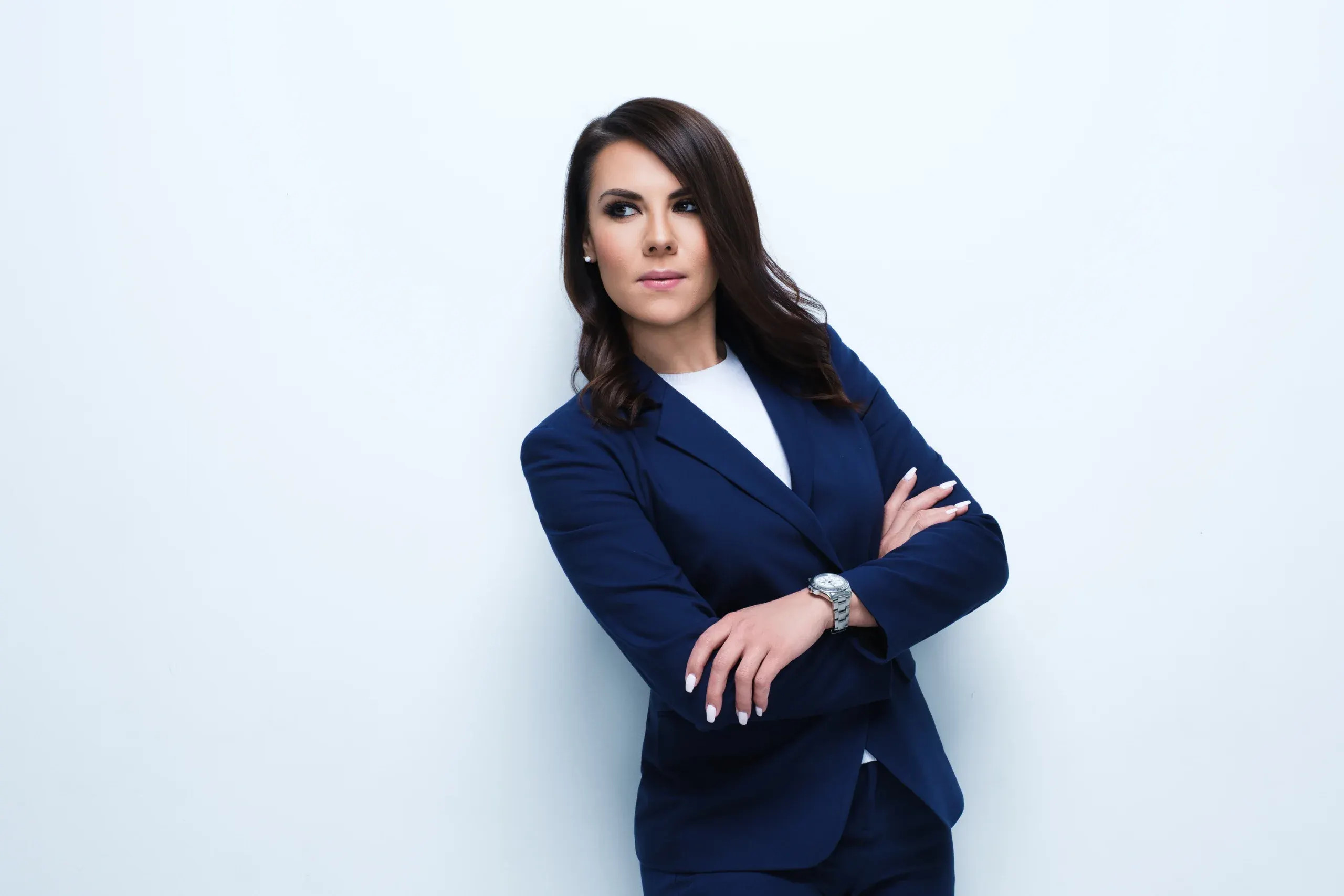 Houston headshot of a woman in a navy blazer, arms crossed, against a bright white wall